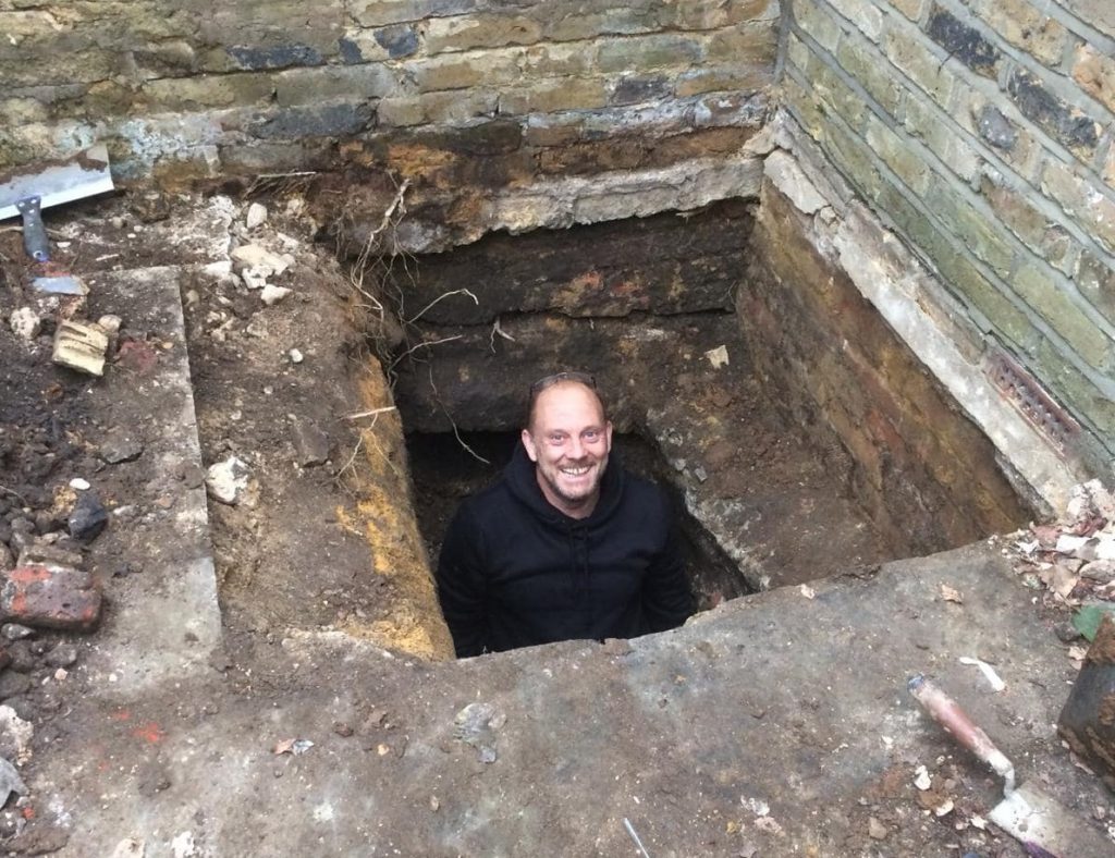 builder in a hole working on basement tanking